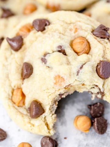 Close up of Caramel Chocolate Chip Cookies in a pile with a bite taken out of the one at the front.