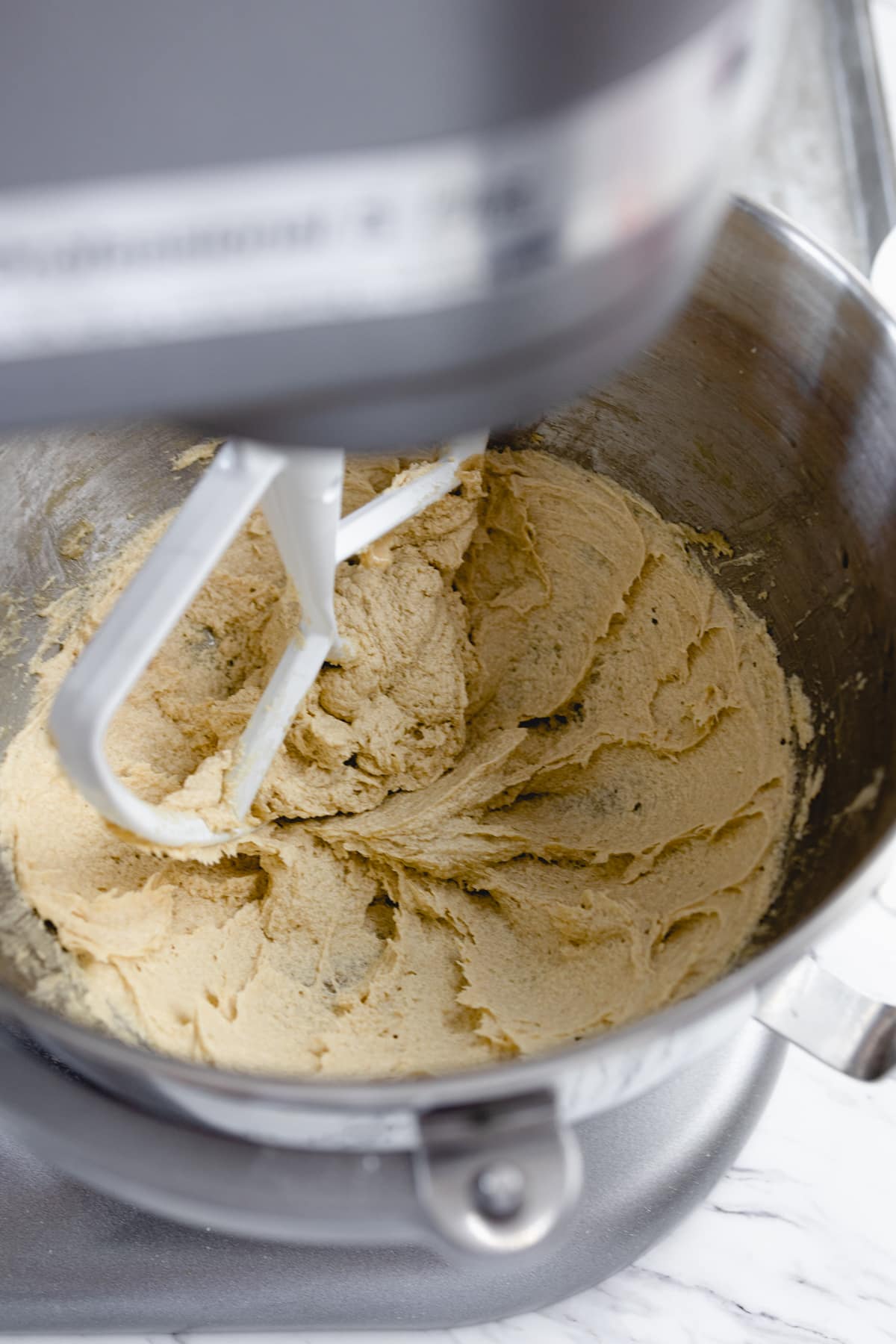 Close up of the bowl of a stand mixer mixing cookie dough.