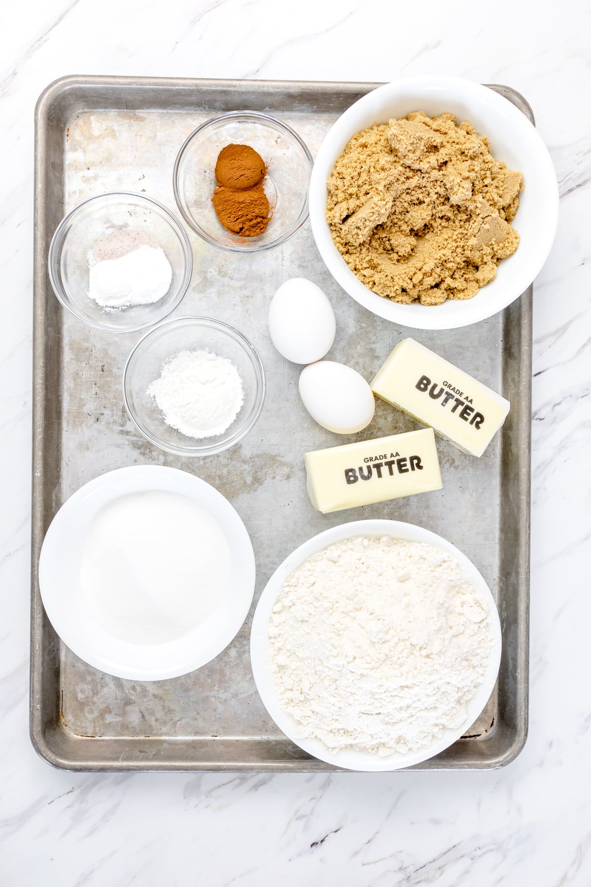 Top view of a baking tray with ingredients needed for coffee cake cookies in small bowls.
