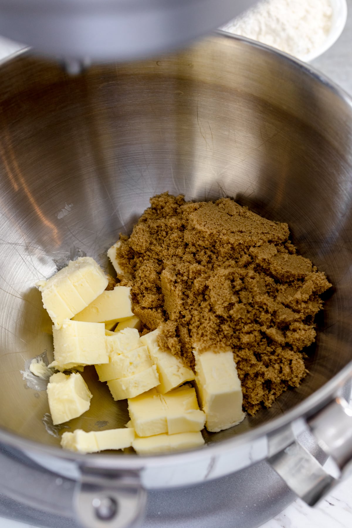 Close up of a bowl of a stand mixer with butter and brown sugar in it.