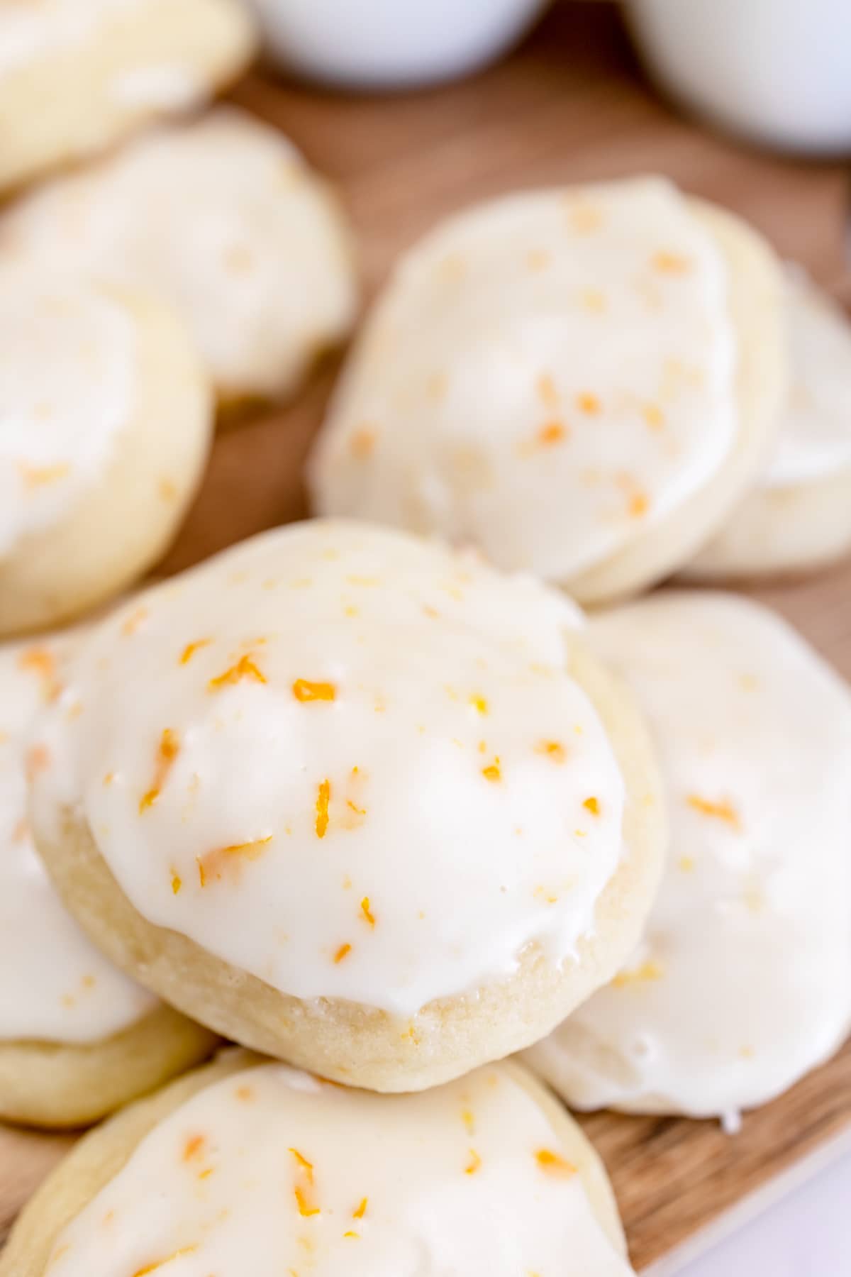 Close up of lemon ricotta cookies in a pile on a brown chopping board.