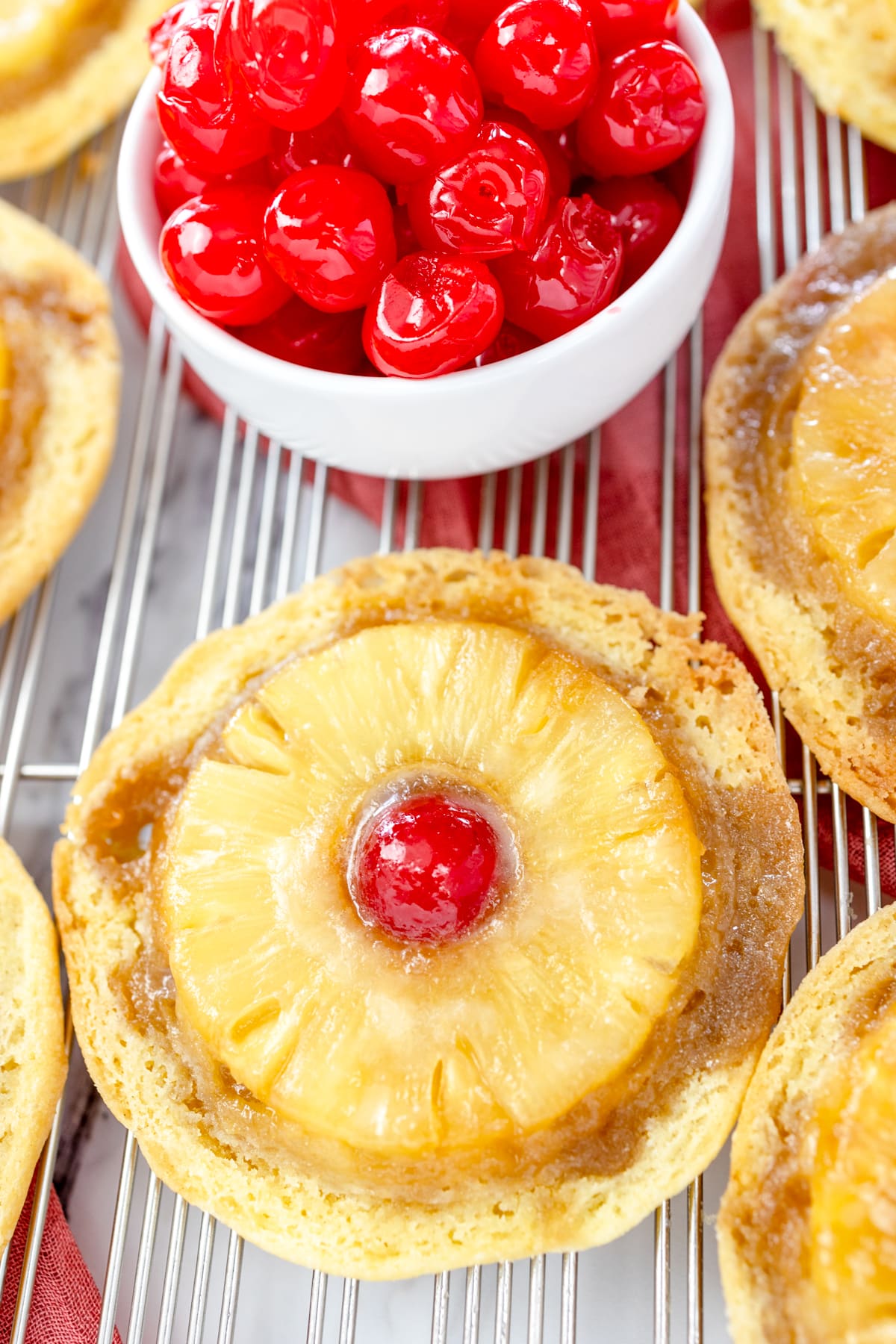 Top view of Pineapple Upside Down Cookies on a wire rack with a small bowl of maraschino cherries in it.