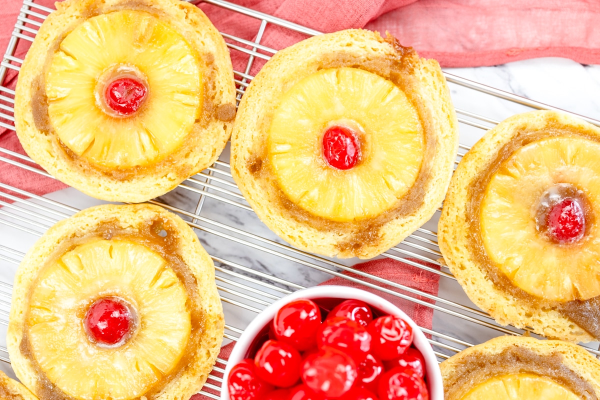 Pineapple Upside Down Cookies with a maraschino cherry in the middle on a wire rack
