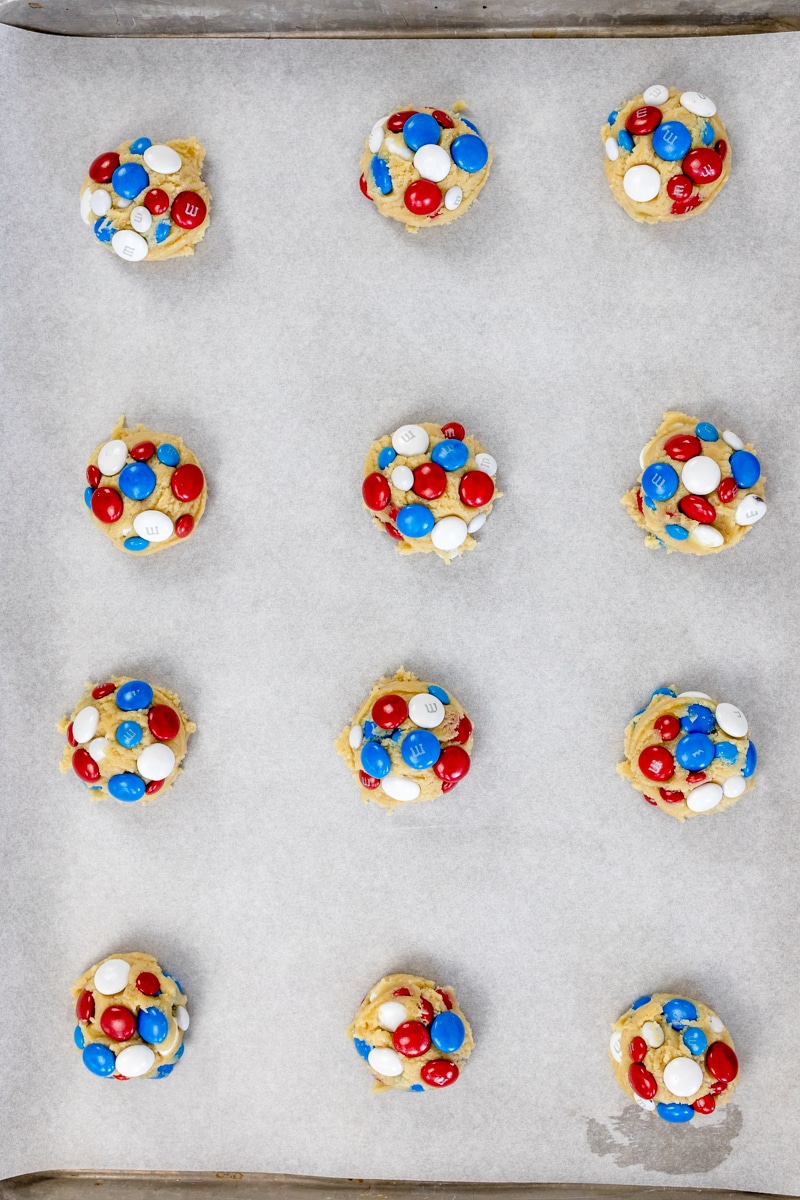 Top view of 4th of July Cookie dough balls on parchment paper on a baking tray.