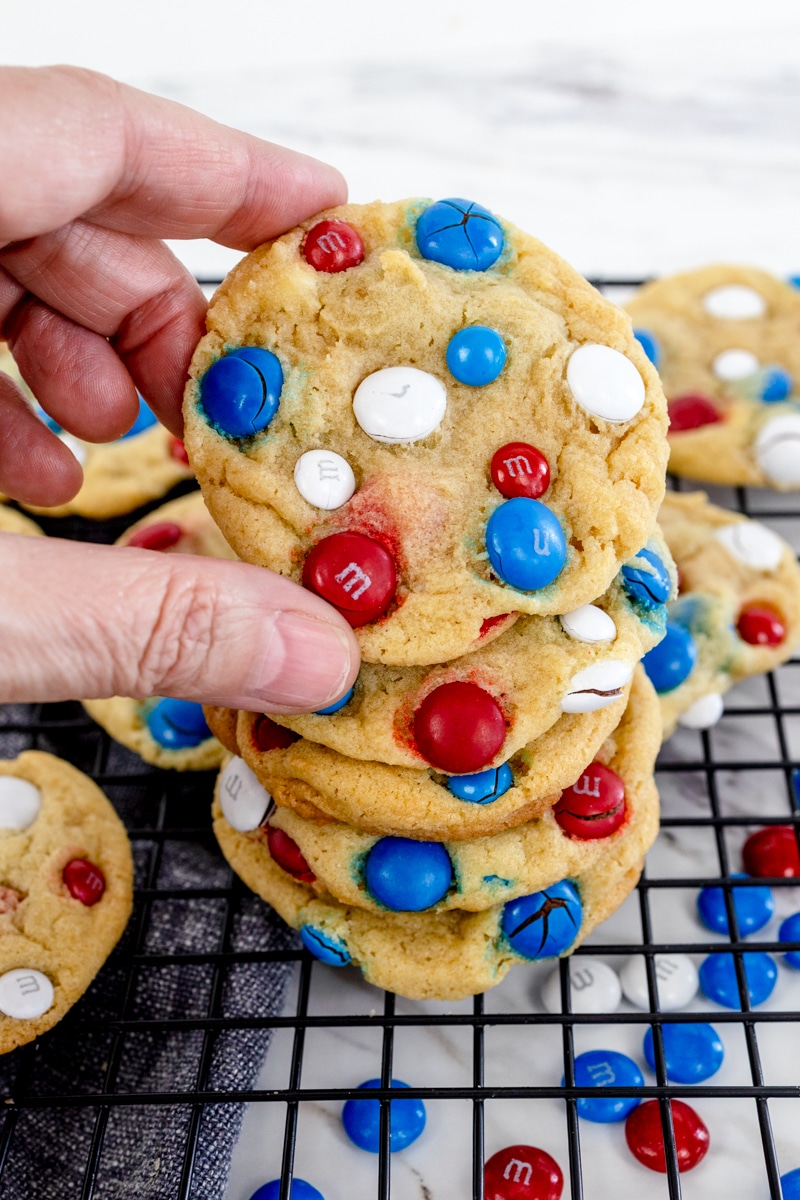 A stack of 4th of July Cookies on a wire rack with the top one being picked up. 