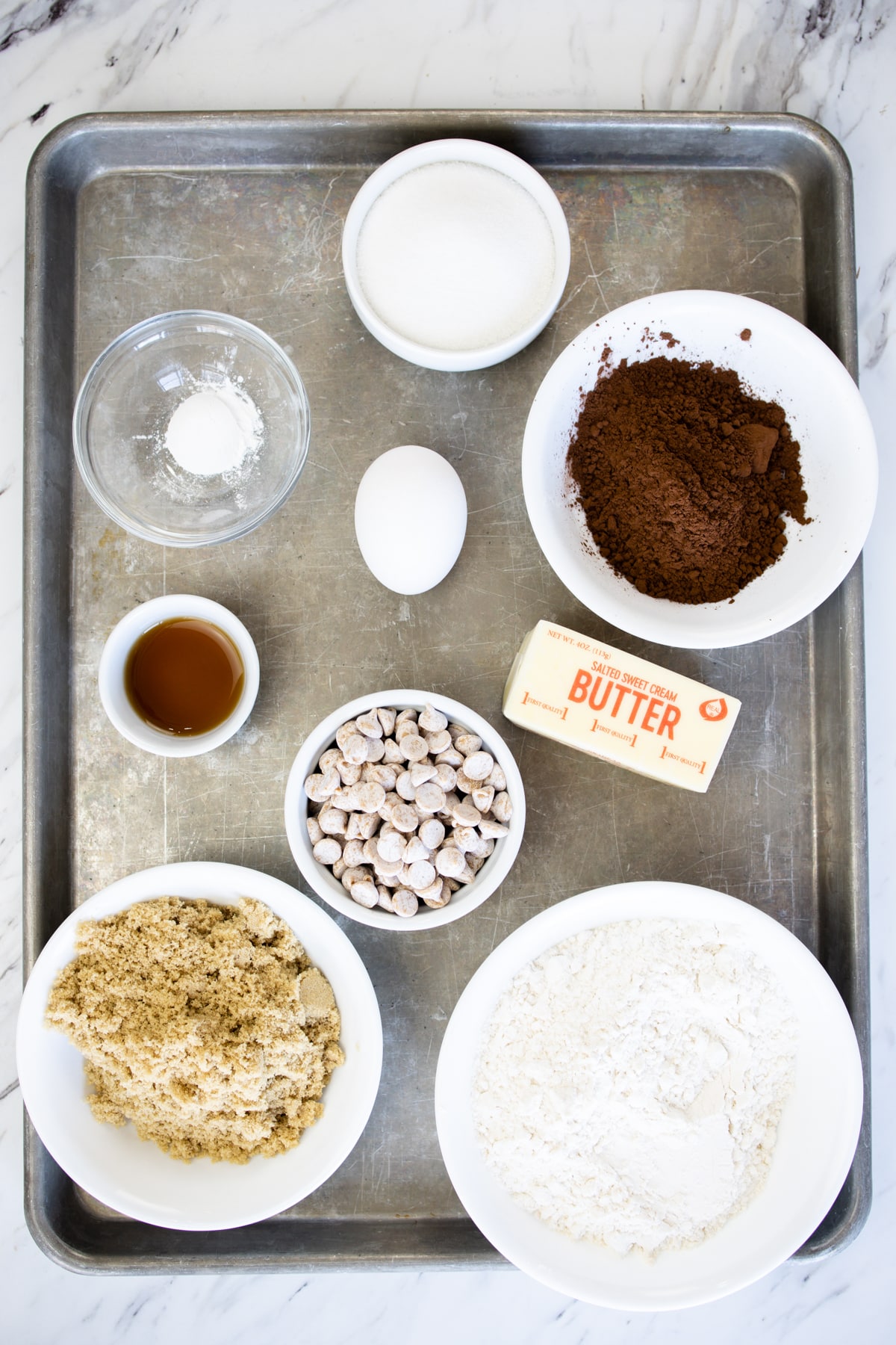 Top view of ingredients needed to make Chocolate Peanut Butter Cookies in small bowls on a bsking tray.