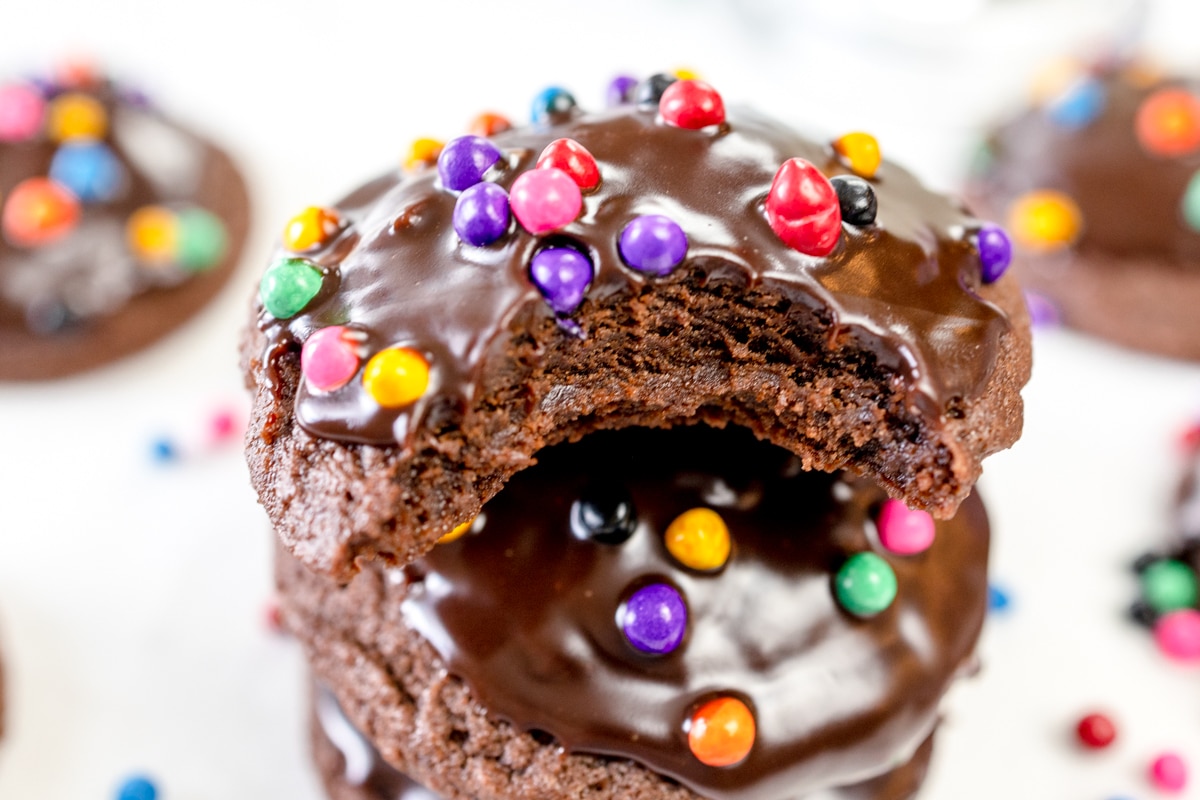 Close up of a Cosmic brownie cookie with a bite taken out of it on top of other cosmic cookies.