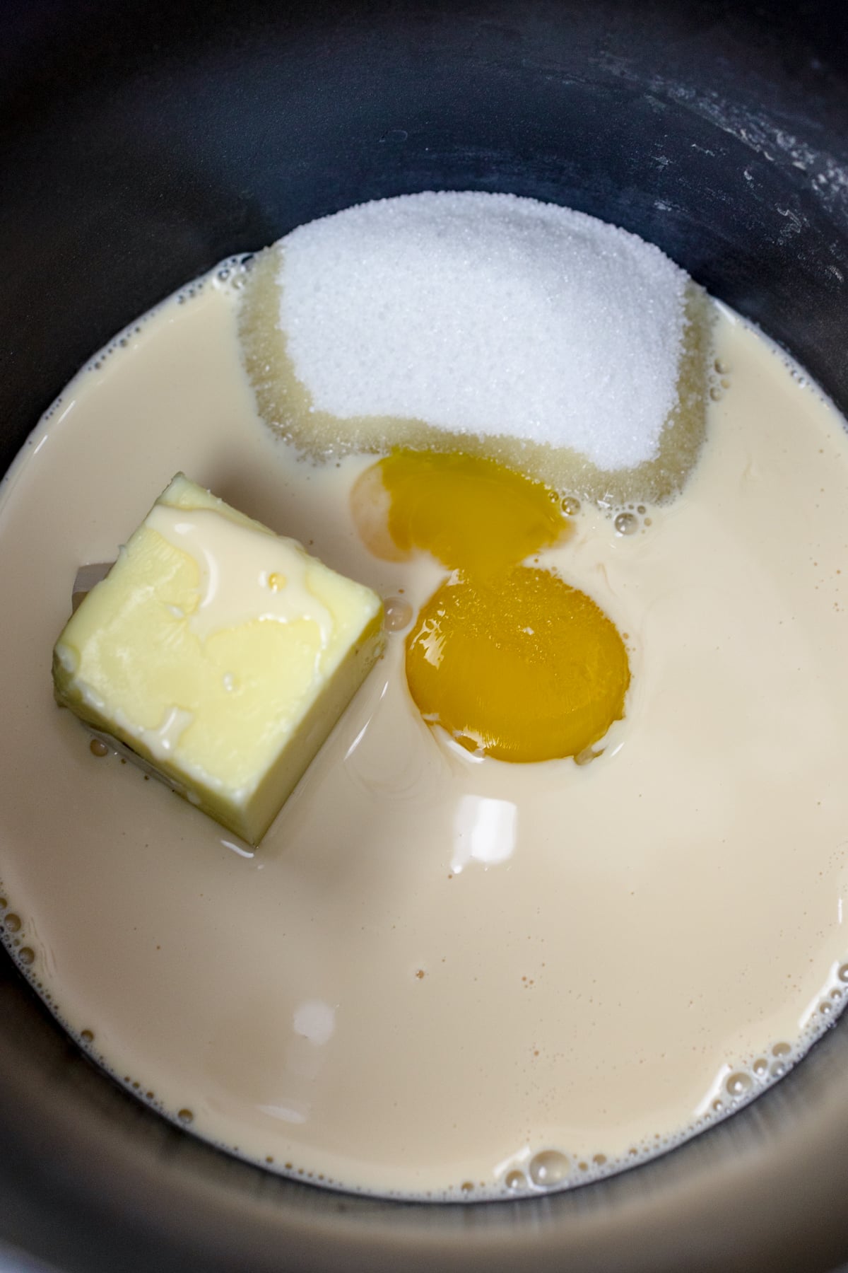 Top view of a pan with cream, sugar, butter, and eggs in it.