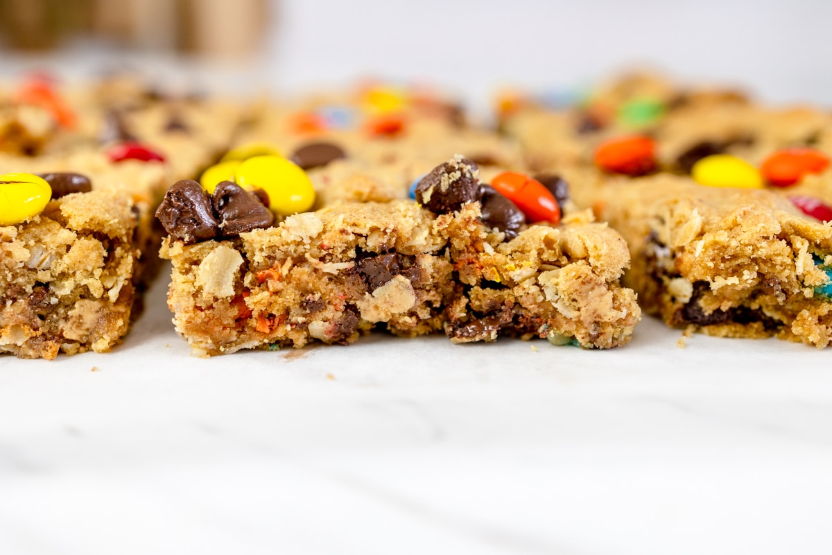 Close up of the profile of monster cookie bars on a white surface.