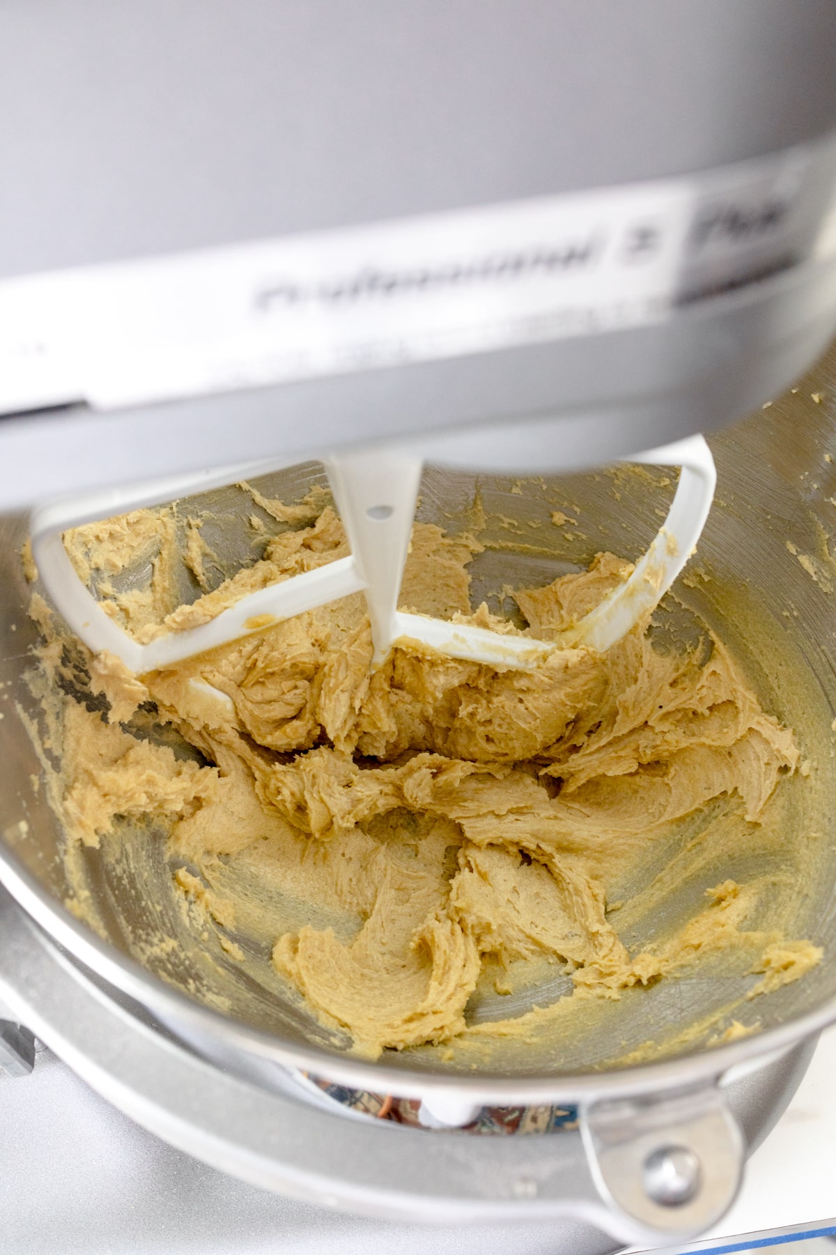 Close up of the bowl of a stand mixer with butter and sugar creamed in it.