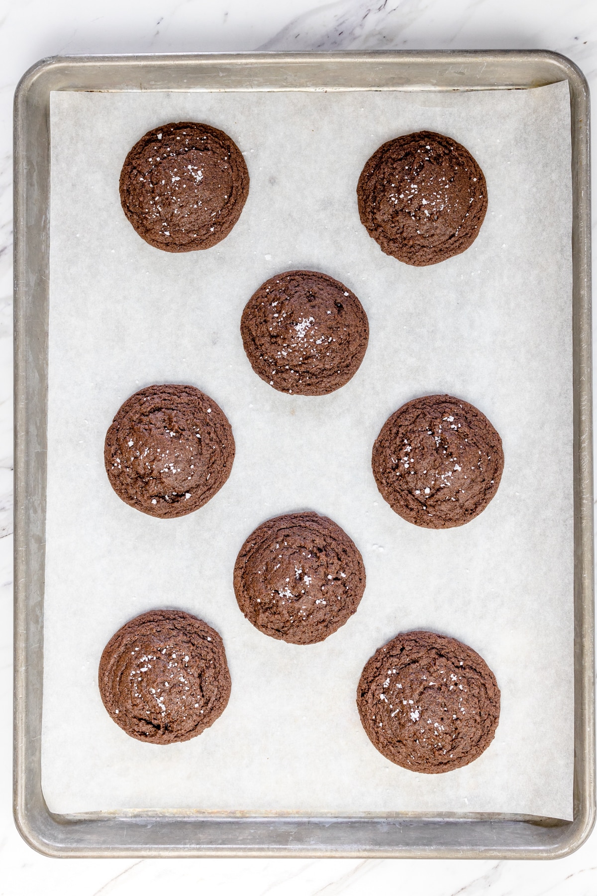 Top view of freshly aked Rolo Cookies on parahcmnet paper on a baking tray.