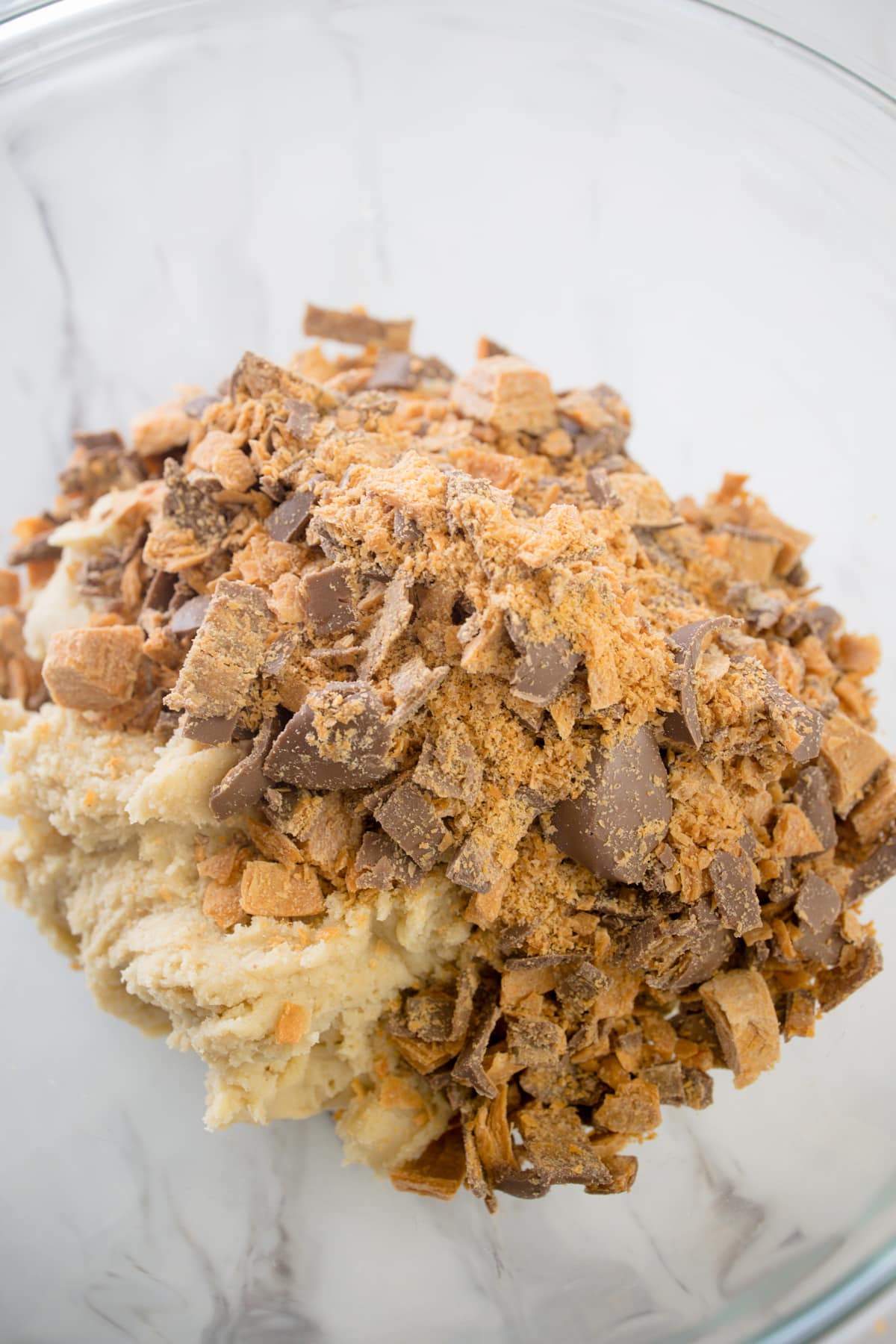 Close up of cookie dough with chopped Butterfinger candies on top.