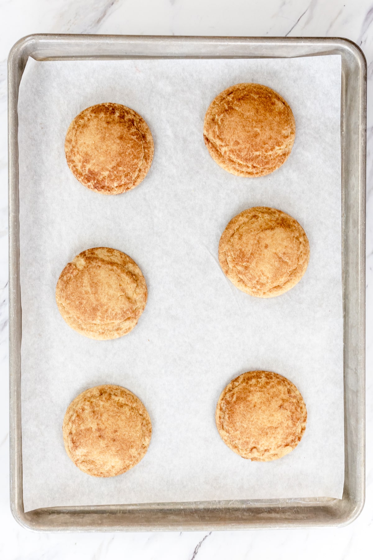 Top view of Churro Cookies cookie dough balls on parchment paper on a baking tray.