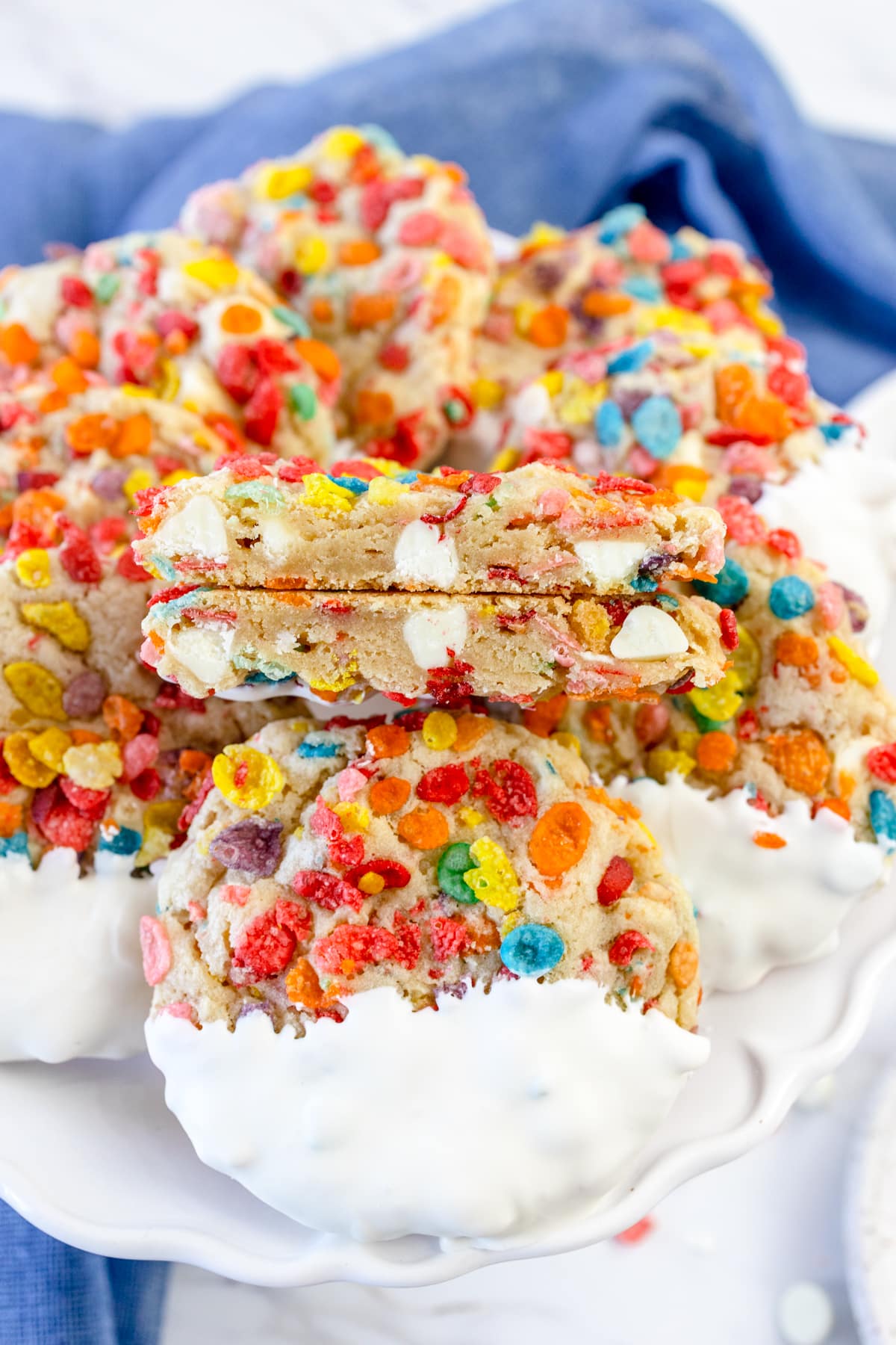 Pile of Fruity Pebbles Cookies with a cookie broken in half sitting on top so you can see the inside.