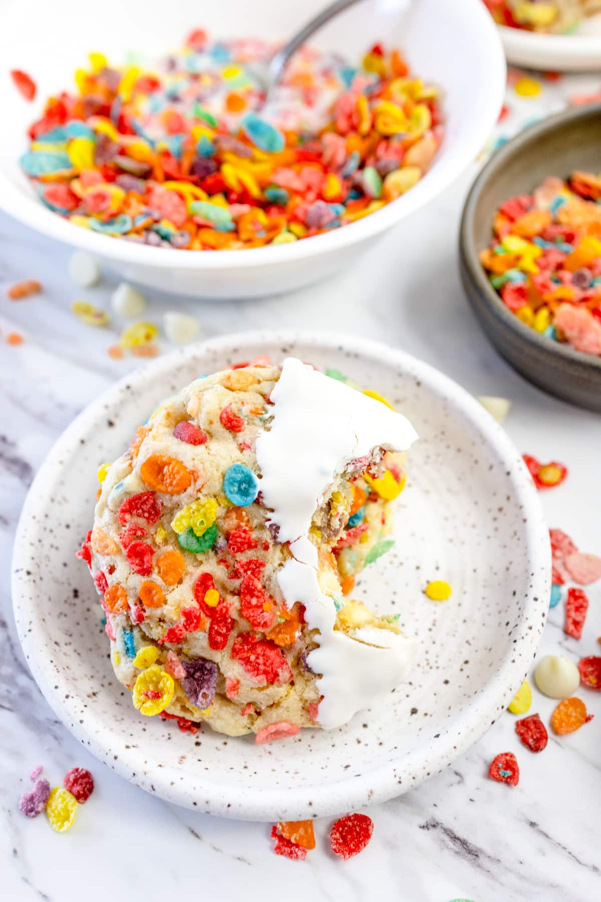 Top view of Fruity Pebbles Cookies on a white plate with a bite taken out of it.