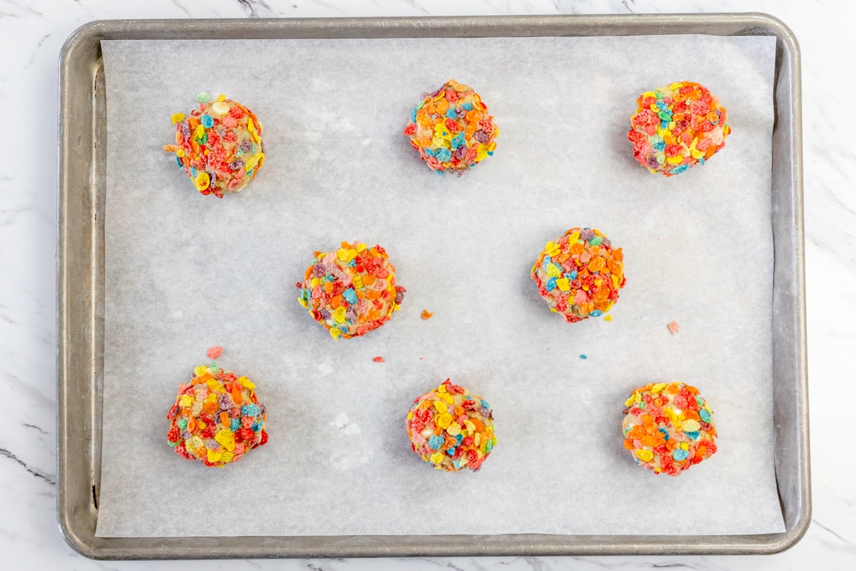 Top view of Fruity Pebbles Cookie dough on parchment paper on a baking tray.