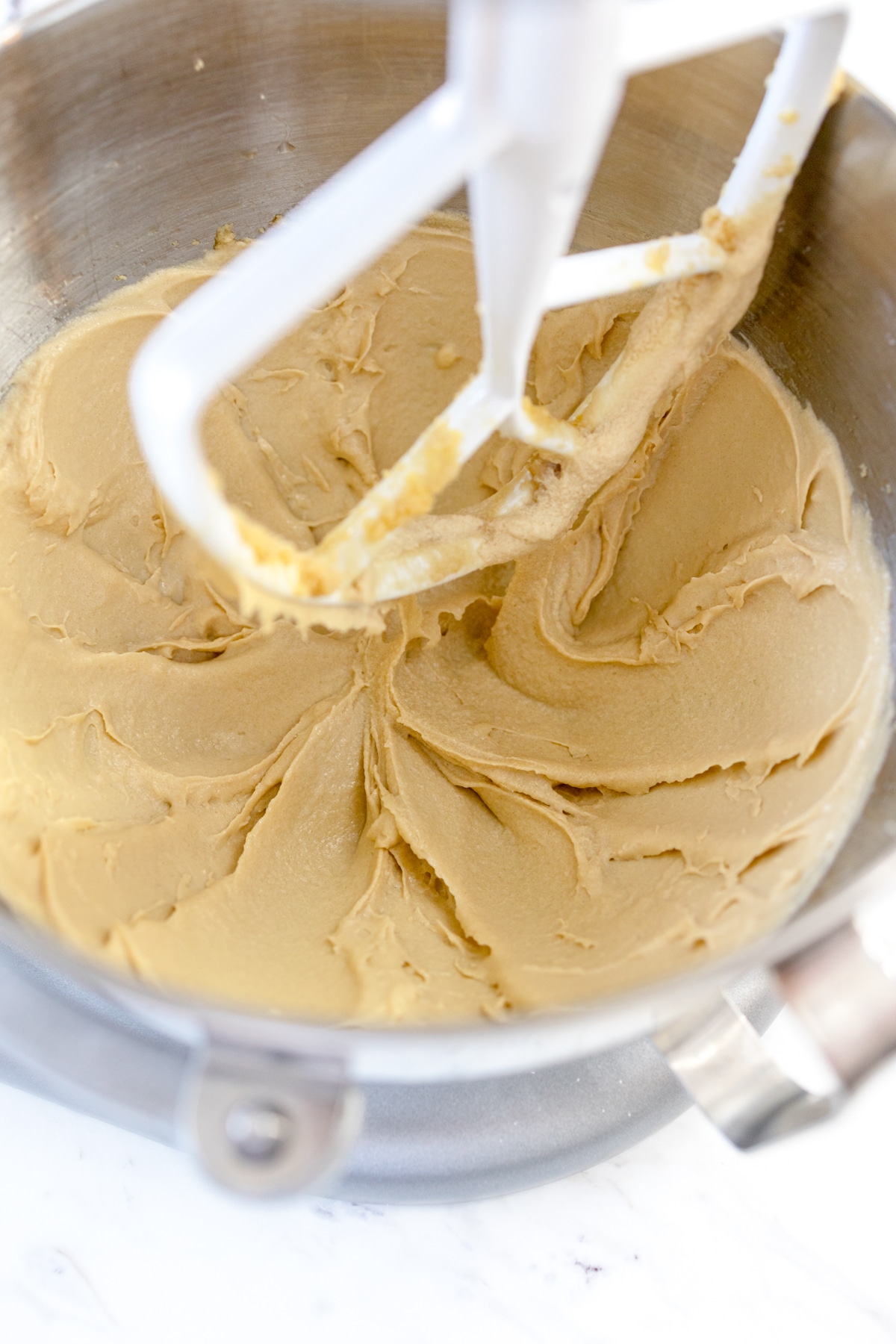 Close up of a stand mixer with a paddle attachment creaming butter and sugar.