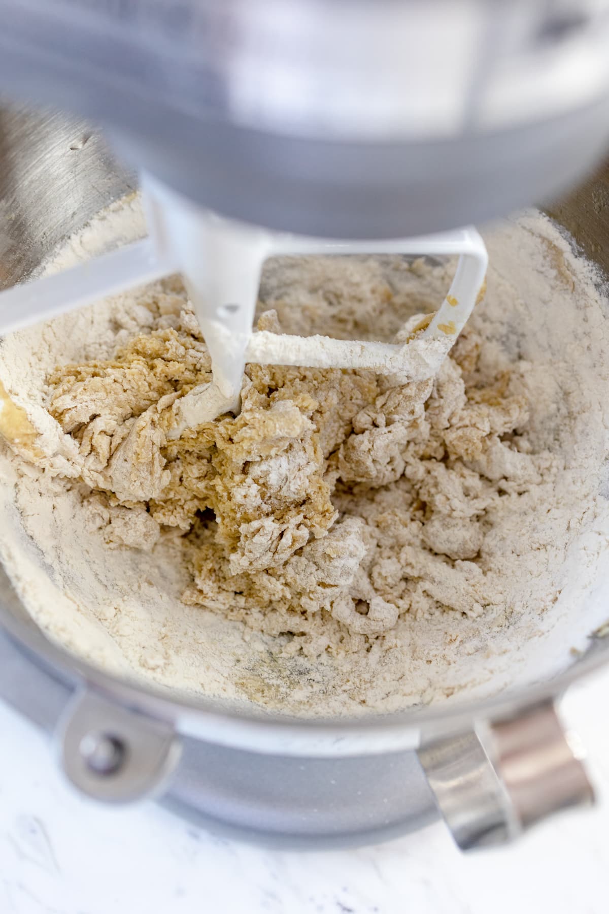 Close up of a stand mixer with a paddle attachment mixing cookie dough.