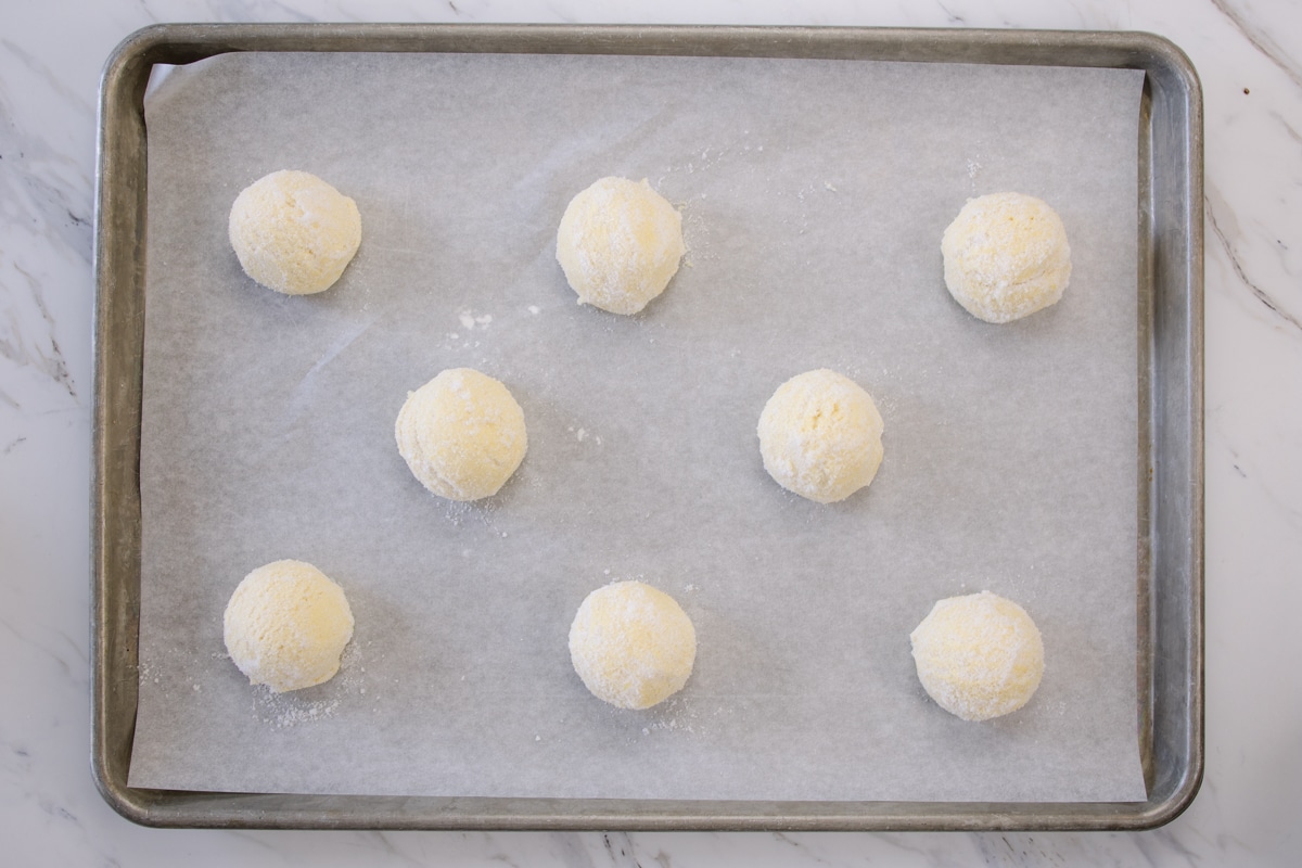 Top view of lemon cookie dough balls on parchment paper on a baking tray.