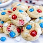 Mini M&M Cookies in a pile on a white surface.