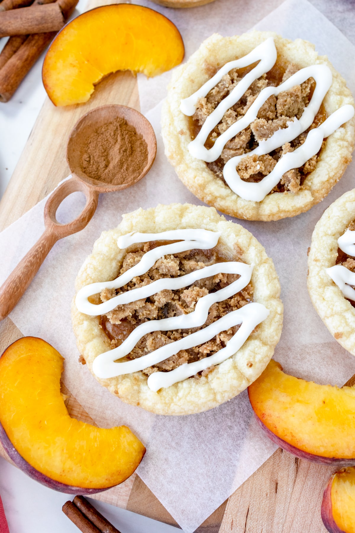 Top view of peach cobbler cookies on a white surface with peach slices around them.