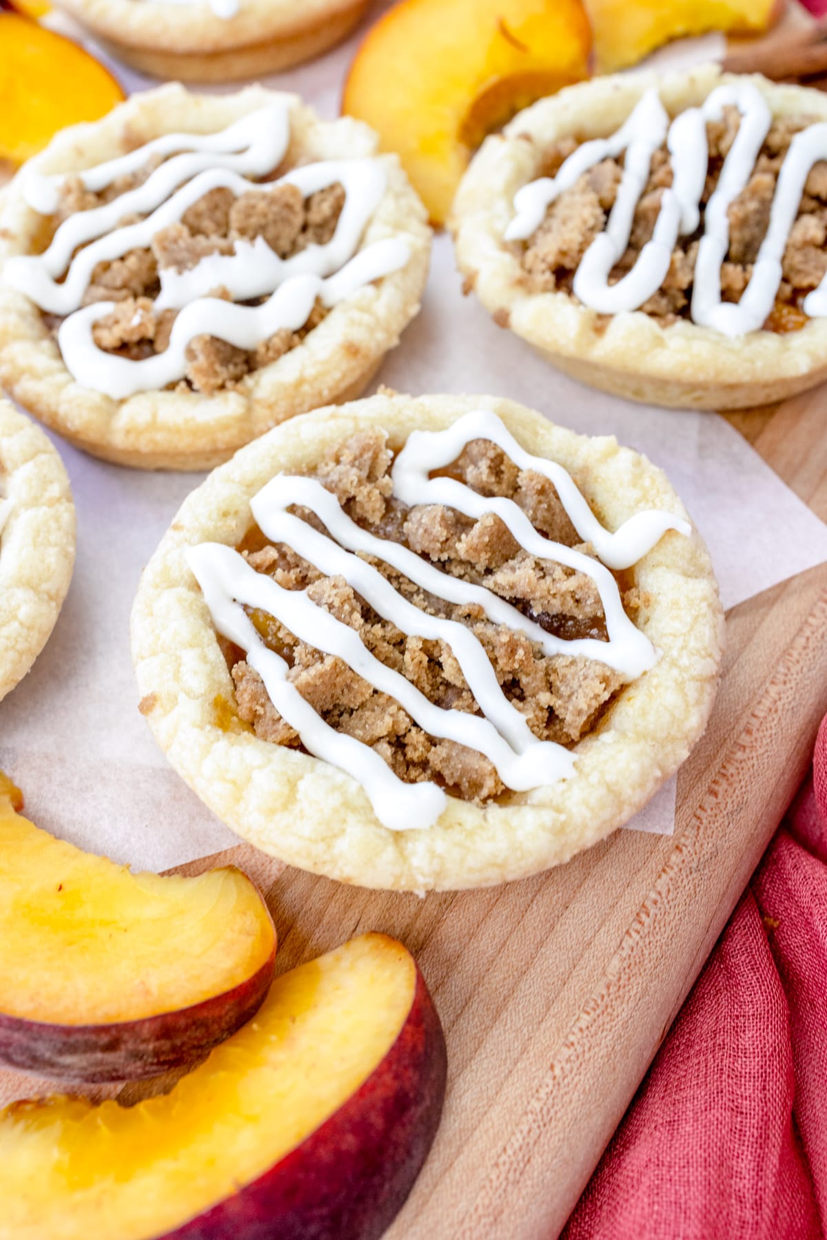Peach cobbler cookies on a white surface with peach slices around them.