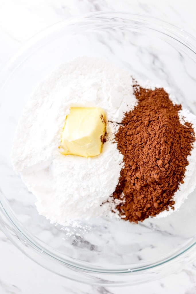 Close up of butter, cocoa powder, and powdered suagr in a misxing bowl.