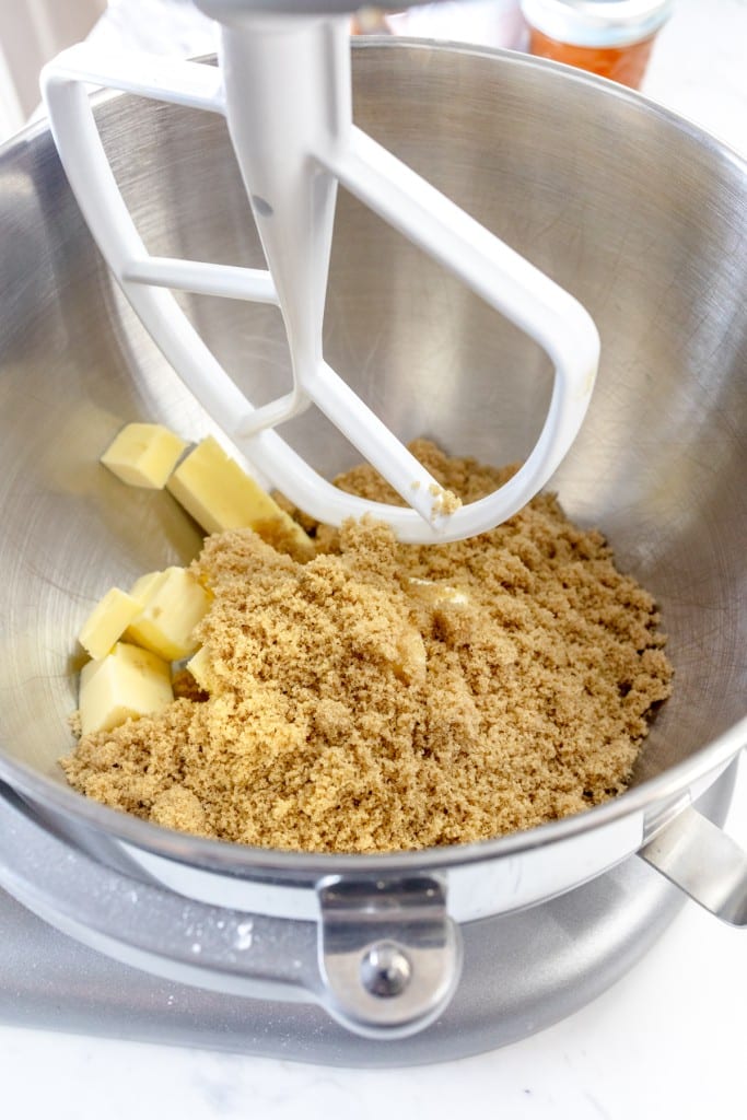 Close up of the bowl of a stand mixer with butter and brown sugar being mixed by a paddle attachmentl.