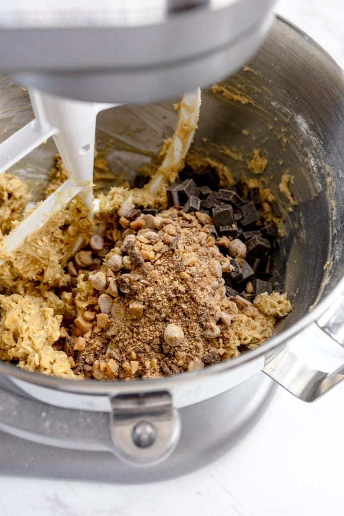 Close up of the bowl of a stand mixer with a cookie dough mixture being combined with spices.