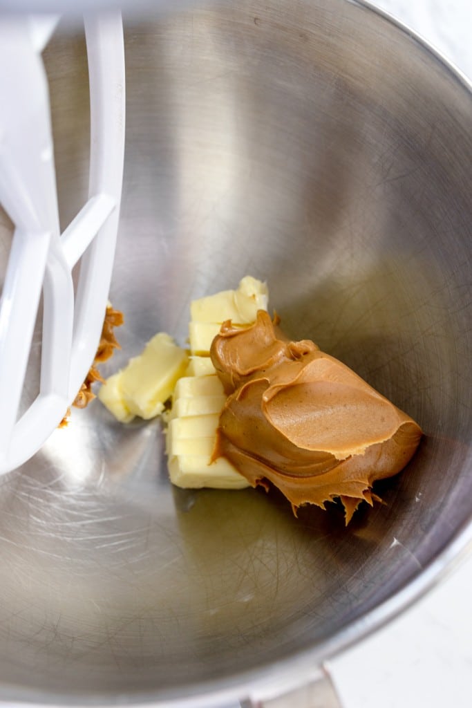 Close up of the bowl of a stand mixer with a paddle attachment with peanut butter and butter in it.