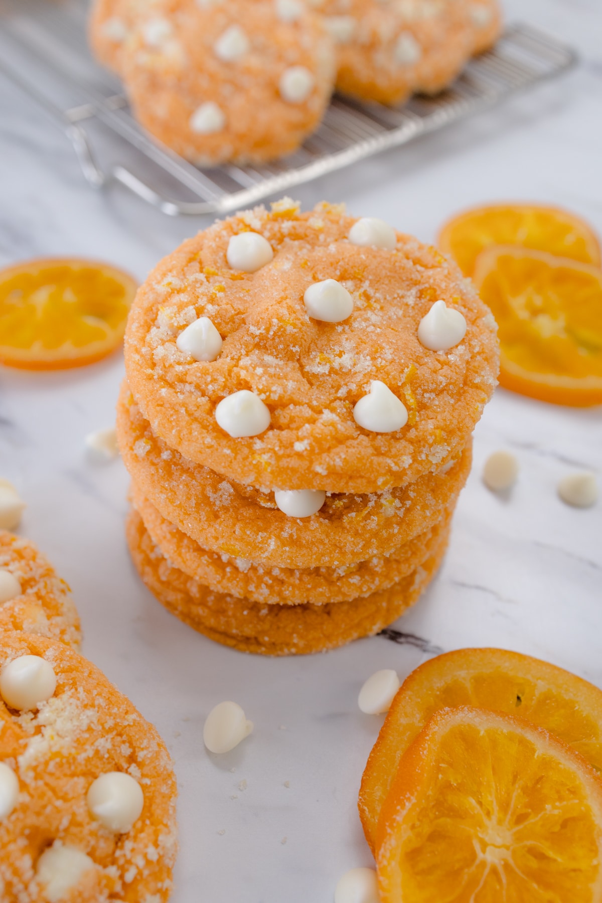 Close up of orange creamsicle cookies in a stack on a white surface.