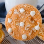Close up of an orange creamsicle cookie resting on a glass of milk.
