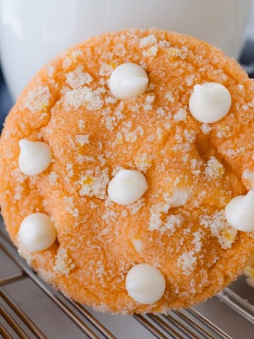 Close up of an orange creamsicle cookie resting on a glass of milk.