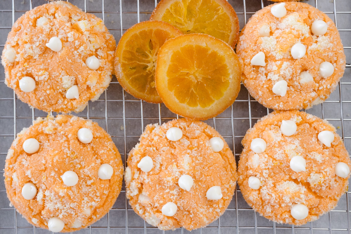Top view of orange creamsicle cookies and orange slices on a wire rack.