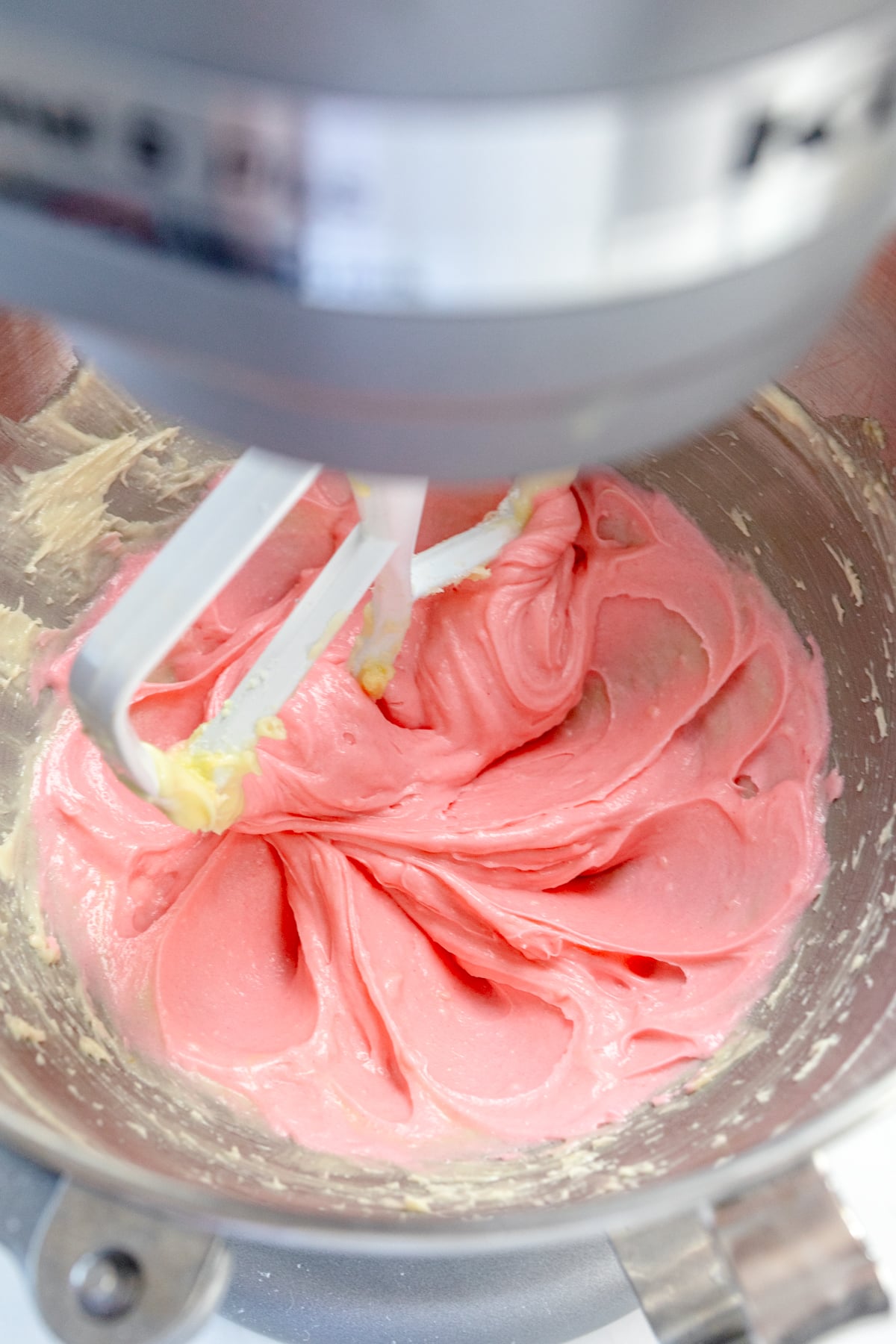 Close up of the bowl of a stand mixer with strawberry cookie dough in it.