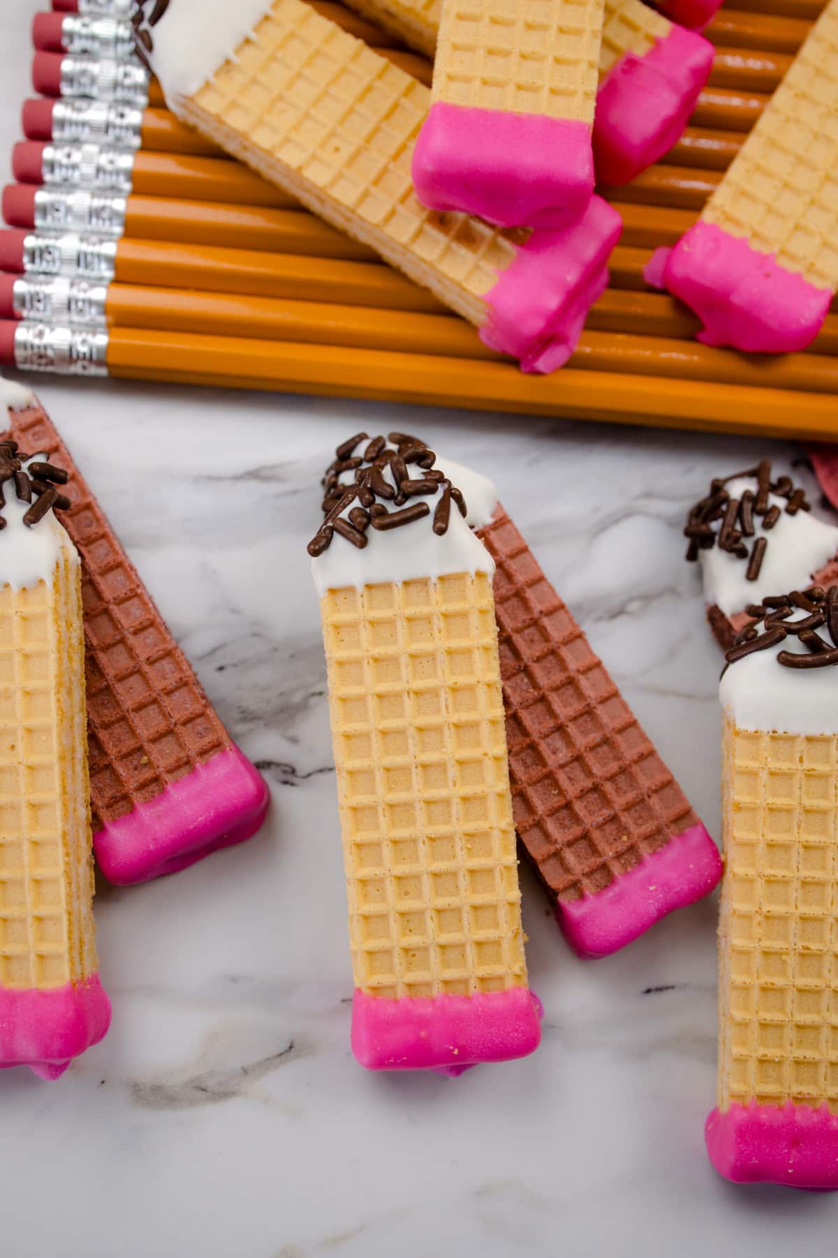 Pencil cookies stacked on top of each other and on top of real pencils.