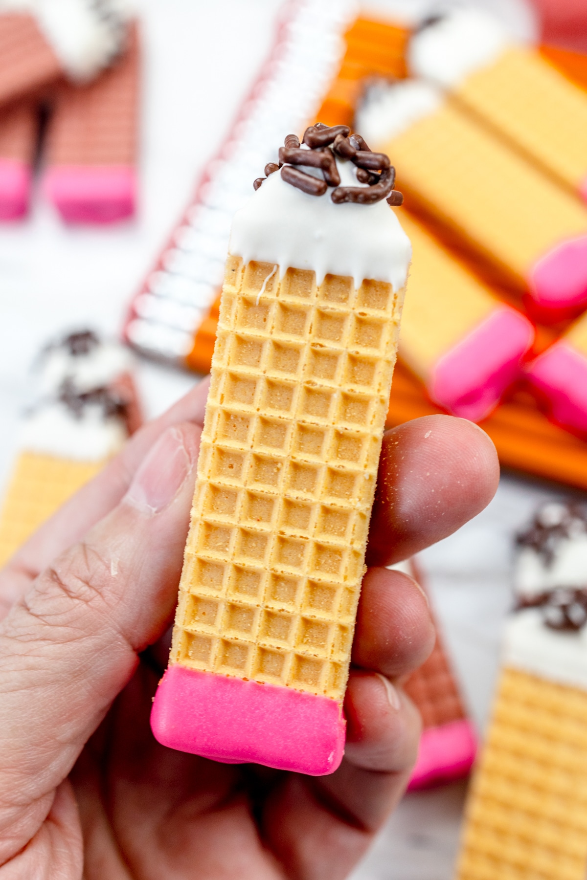 A hand holding a pencil cookie.