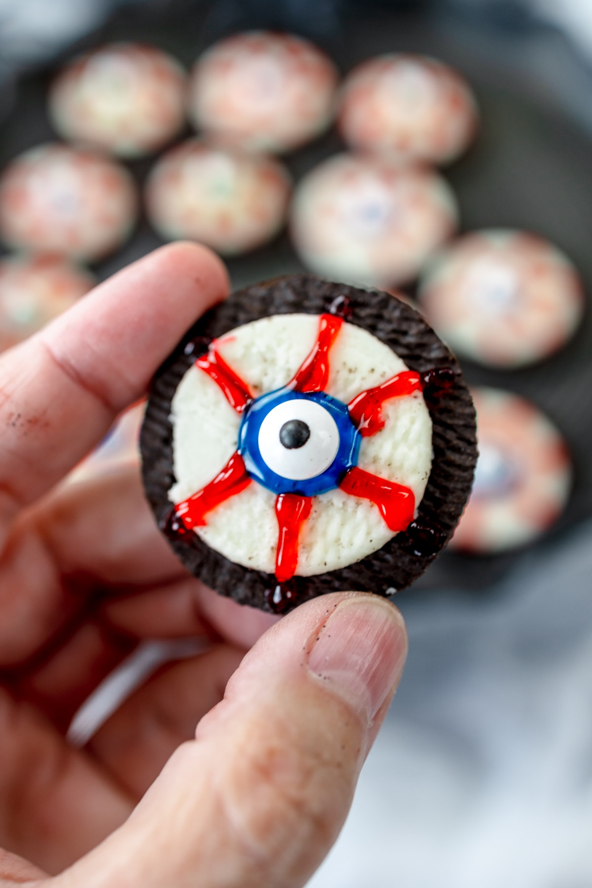 Top view of someone holding up an eyeball cookie in mid air.