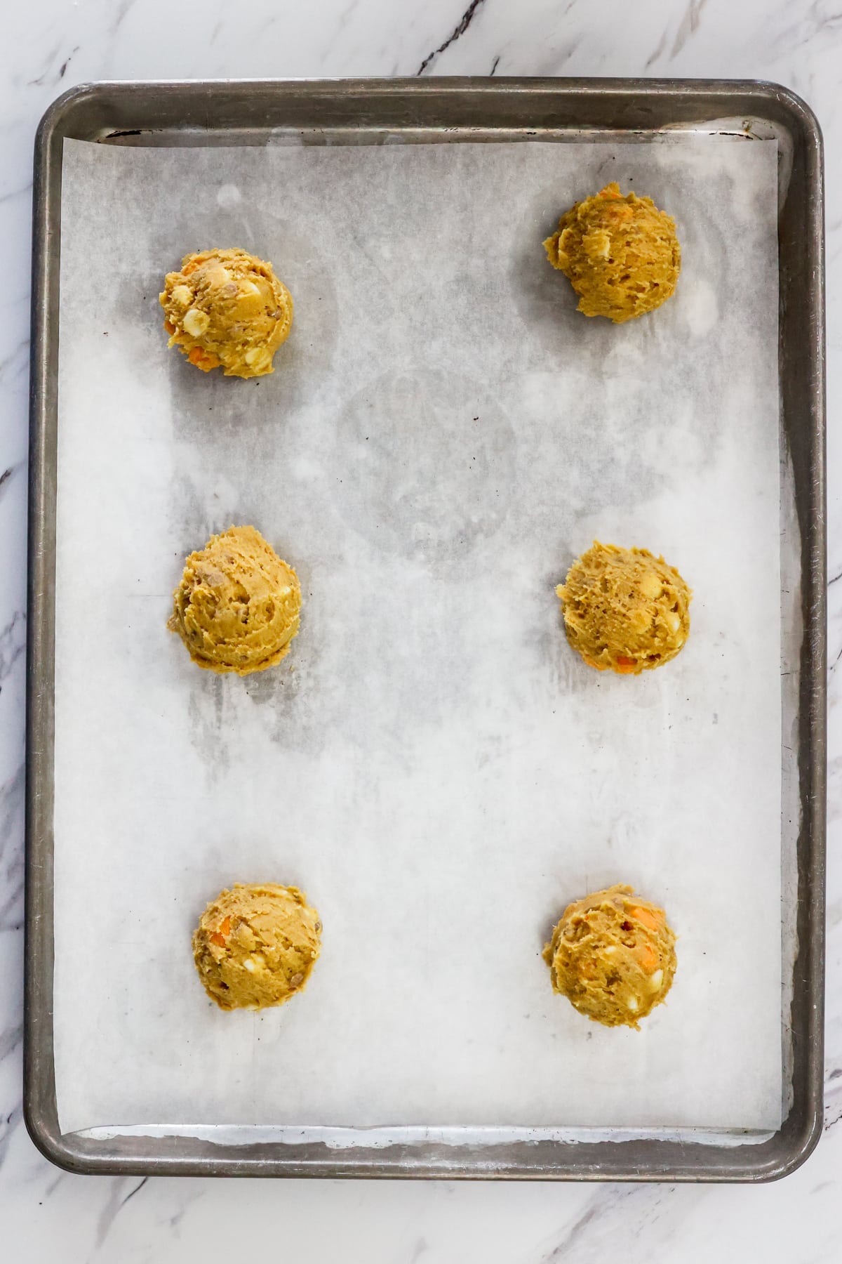 Top view of balls of cookie dough on a baking tray.