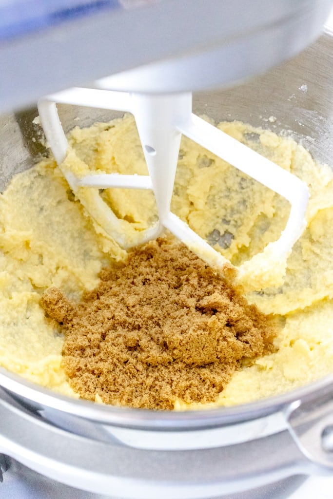 Close up of the bowl of a stand mixer with a paddle attachment mixing creamed butter and brown sugar.
