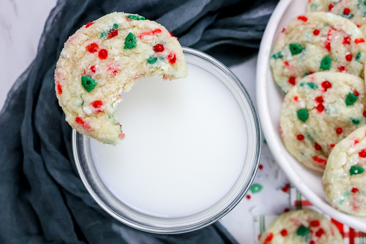 Top view of a Christmas Sugar Cookie with a bite taken out of it, resting on a glass of milk.