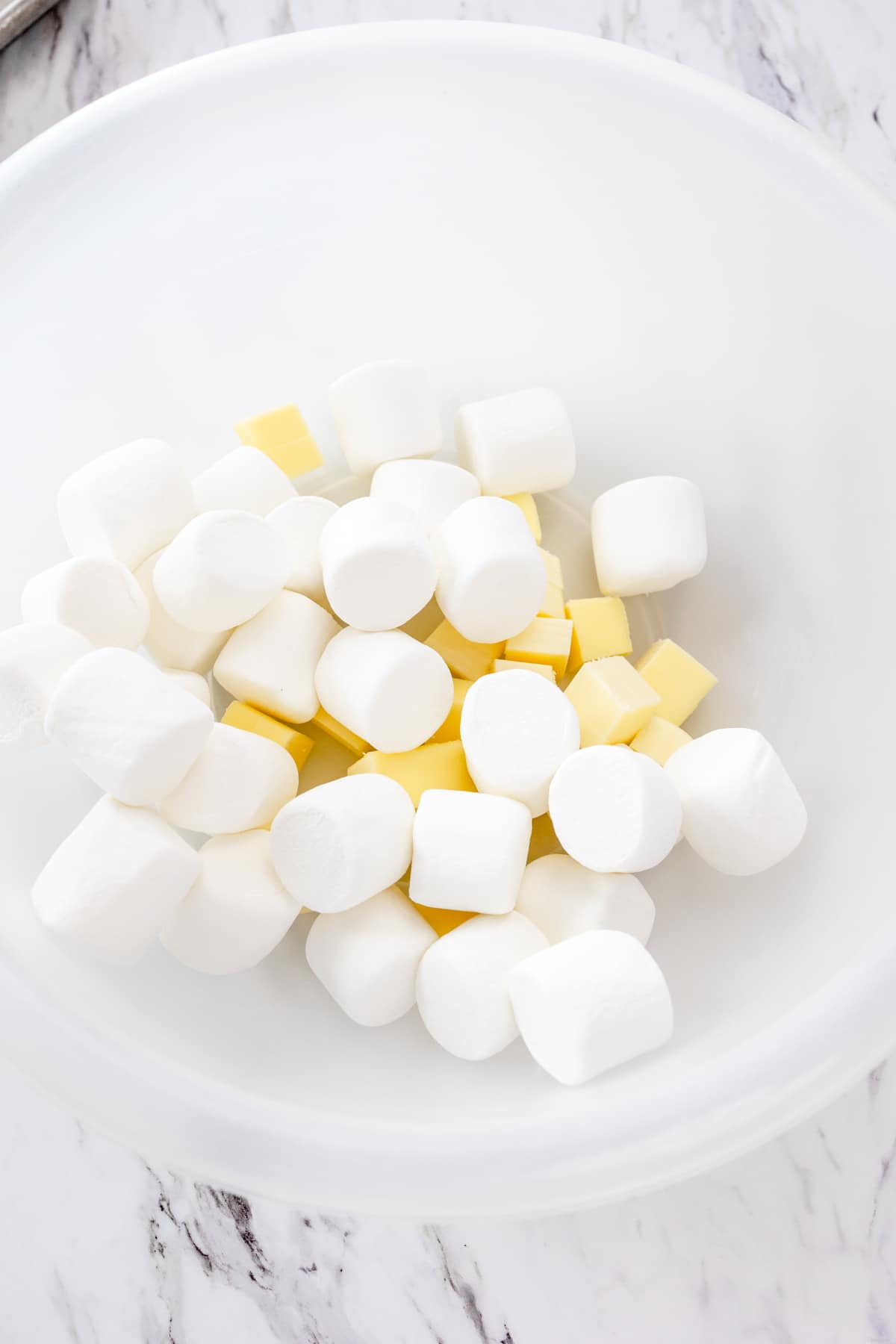 Top view of marshmallows and butter in a mixing bowl.