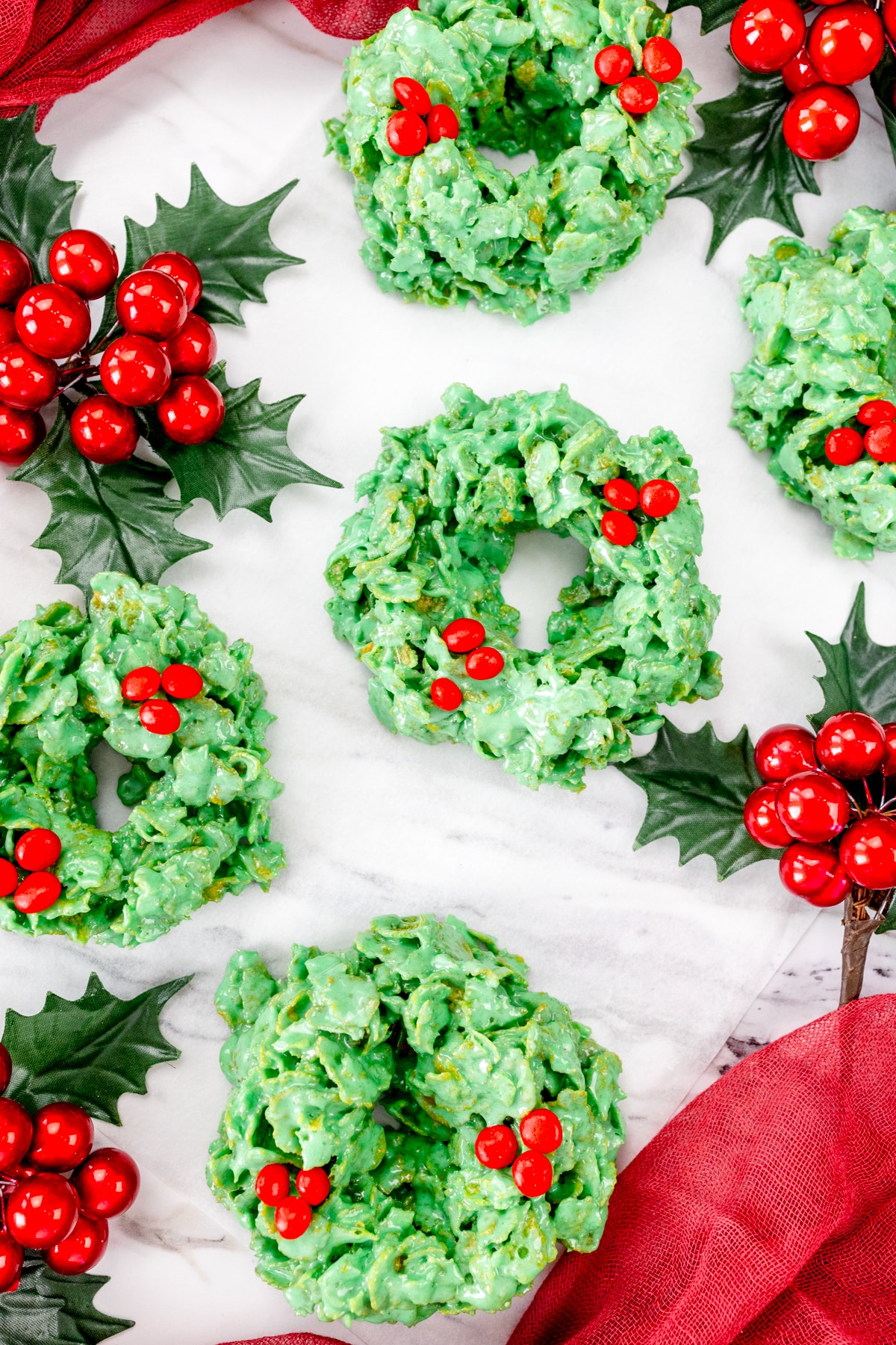 Top view of Christmas Wreath Cookies on a white surface with Christmas decorations.
