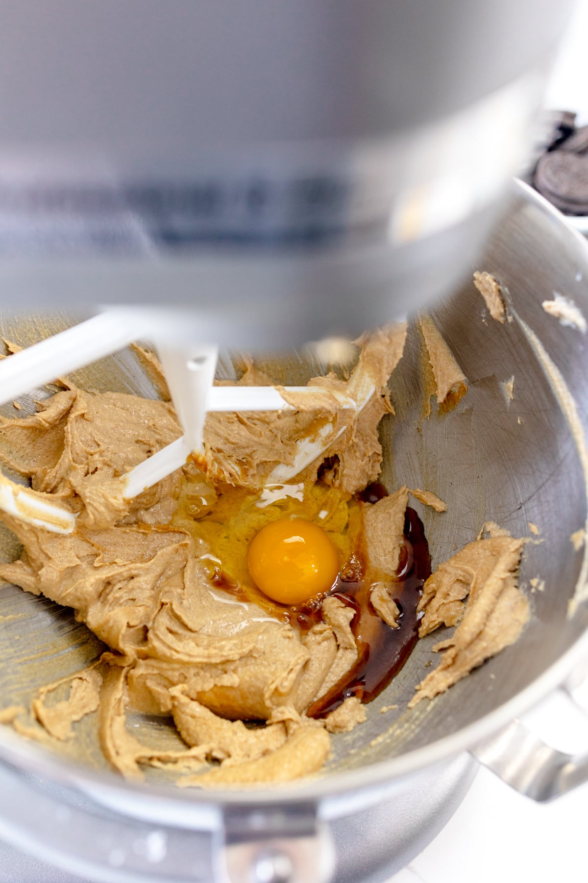 Close up of the bowl of a stand mixer with a creamed mixture in it with an egg on top.