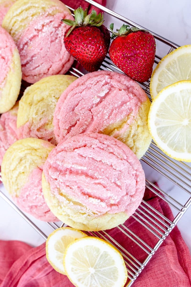 Top view of Strawberry Lemon Cookies on a wire rack, surrounded with strawberries and slices of lemon.