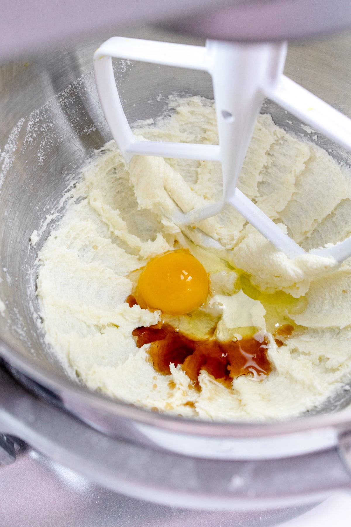 Close up of the bowl of a stand mixer with a creamed mixture in it with an egg on top.