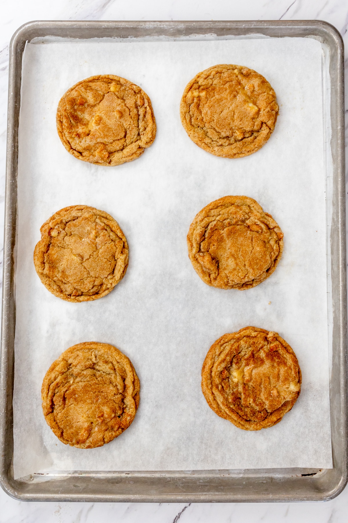 Top view of baking tray lined with parchment paper with freshly baked Caramel Apple Cookies on it.