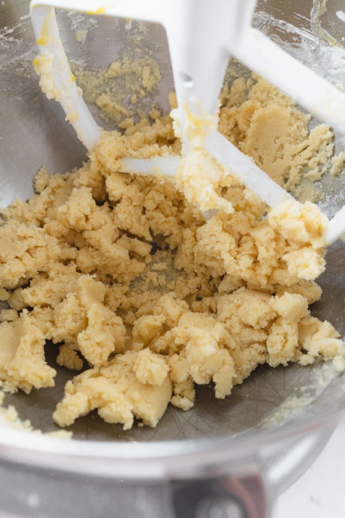 Close up of a butter and sugar mixture being creamed in the bowl of a stand mixer with a paddle attachment.