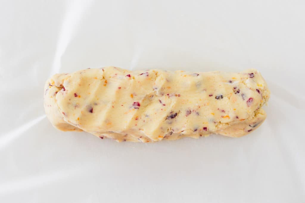Top view of a log of cranberry orange cookie dough on a baking tray.