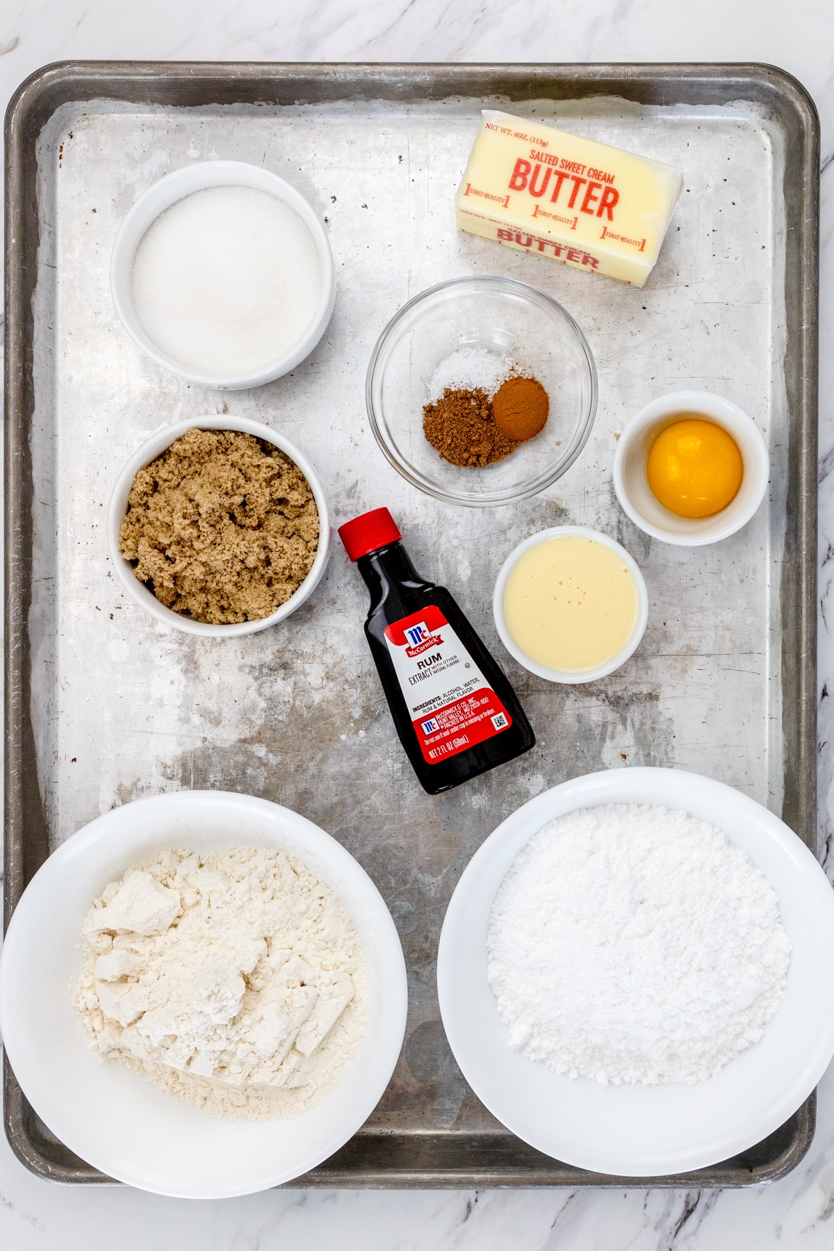 Top view of ingredients needed to make Eggnog Thumbprint Cookies in small bowls on a baking tray.